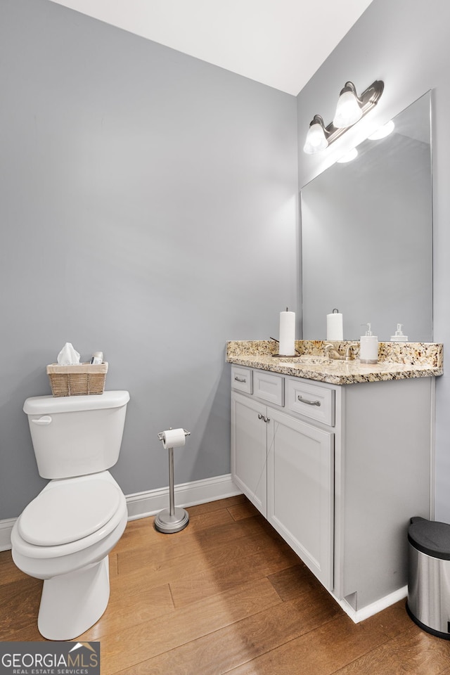 bathroom featuring wood finished floors, baseboards, toilet, and vanity