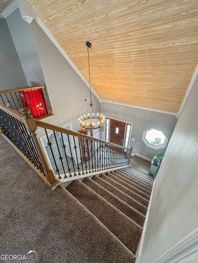 stairway featuring wooden ceiling, crown molding, a chandelier, carpet, and vaulted ceiling
