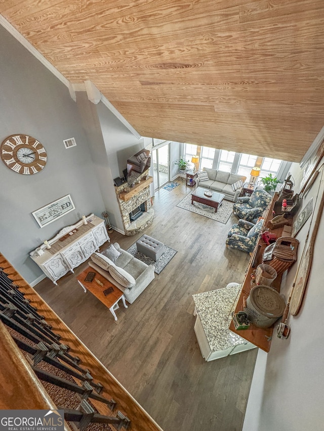 living area featuring wooden ceiling, healthy amount of natural light, wood finished floors, ornamental molding, and a fireplace