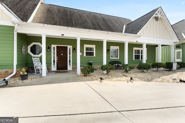 view of front of property with a porch, board and batten siding, and roof with shingles