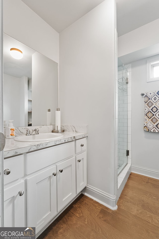full bathroom with baseboards, a shower stall, wood finished floors, and vanity