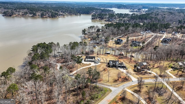 aerial view of property and surrounding area featuring a heavily wooded area and a large body of water