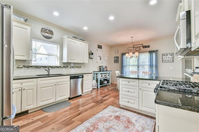 37 Wood Duck Pt, Jefferson, GA 30549 - kitchen featuring appliances with stainless steel finishes, ornamental molding, white cabinets, a peninsula, and light wood-style floors