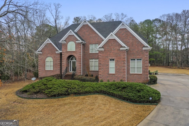 view of front facade with brick siding and a front lawn