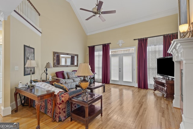 living area with ceiling fan, french doors, high vaulted ceiling, light wood finished floors, and ornamental molding
