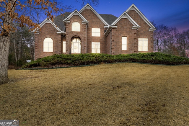 view of front of property with a lawn and brick siding
