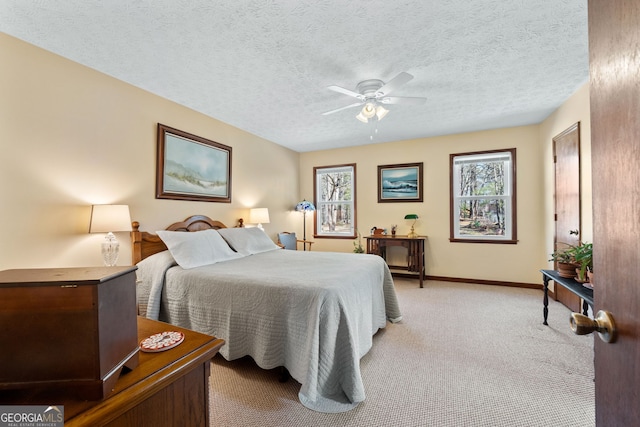 bedroom featuring baseboards, ceiling fan, a textured ceiling, and light colored carpet