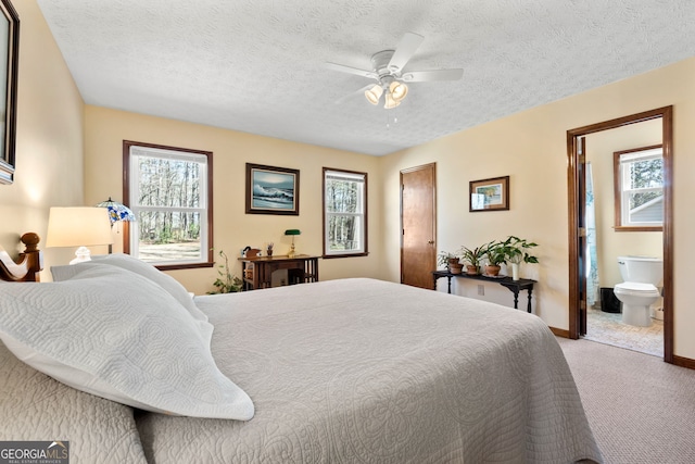 carpeted bedroom with baseboards, a textured ceiling, ensuite bath, and multiple windows