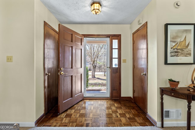 foyer with a textured ceiling, baseboards, and visible vents