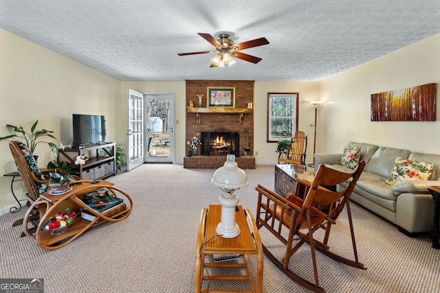 carpeted living room with a textured ceiling, ceiling fan, and a fireplace