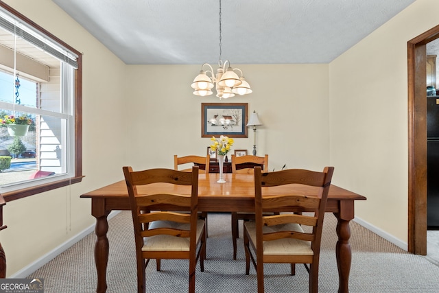 carpeted dining room with baseboards and a chandelier