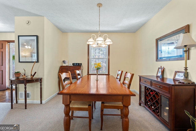 carpeted dining space featuring a textured ceiling, baseboards, a chandelier, and visible vents