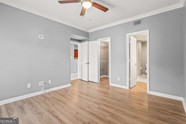 1502 River Green Dr NW Unit 1502, Atlanta, GA 30327 - unfurnished bedroom with a walk in closet, visible vents, crown molding, light wood-type flooring, and baseboards