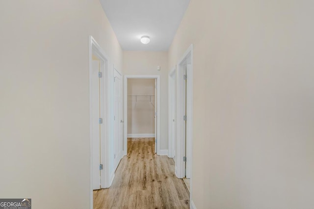 corridor with light wood-style floors and baseboards