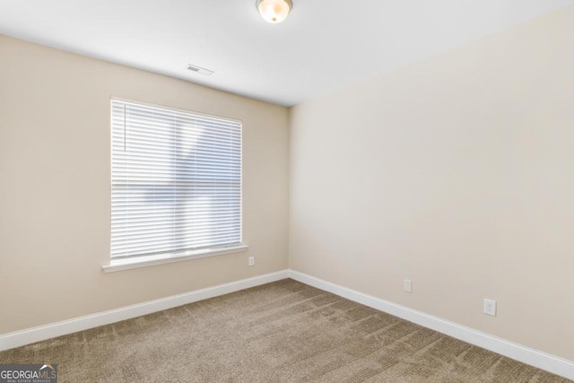 empty room featuring carpet floors, baseboards, and visible vents