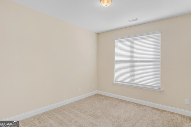 carpeted spare room with baseboards, visible vents, and a healthy amount of sunlight