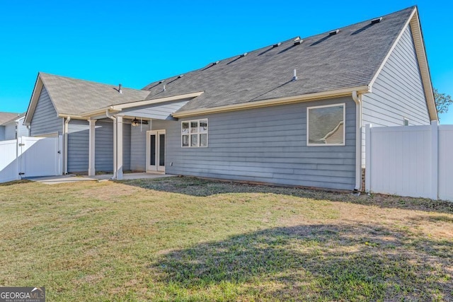 back of house featuring a lawn, a gate, fence, a patio, and a shingled roof