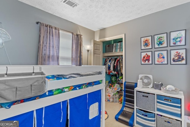 carpeted bedroom with a closet, a textured ceiling, and visible vents