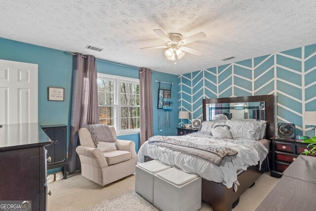 bedroom with visible vents, a textured ceiling, carpet floors, and an accent wall