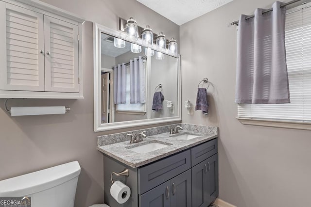 bathroom with double vanity, a sink, and toilet