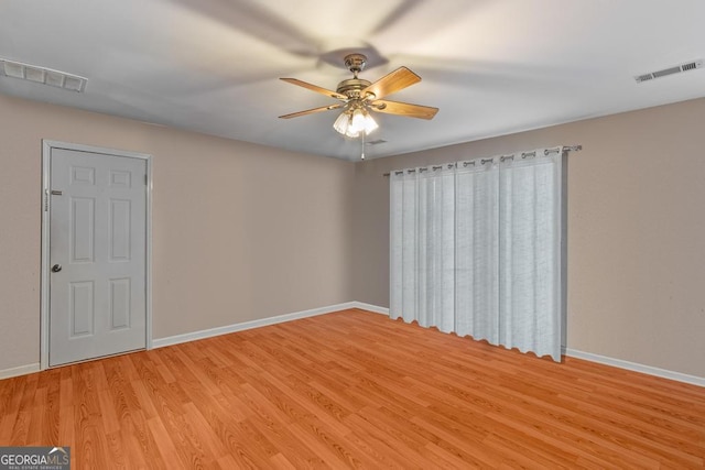 spare room featuring a ceiling fan, baseboards, visible vents, and light wood finished floors