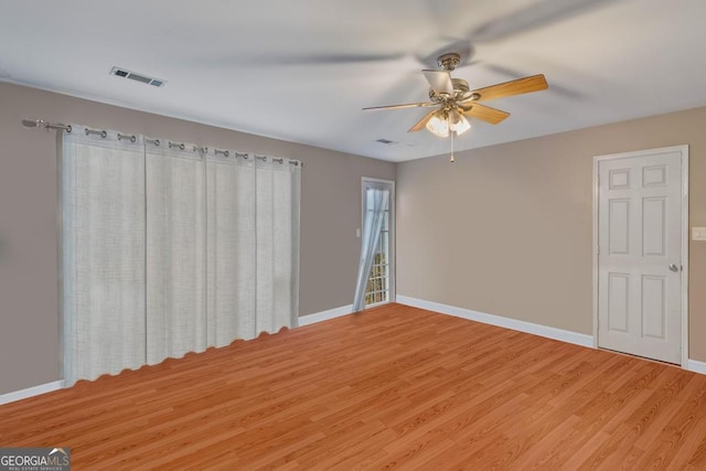 empty room with baseboards, ceiling fan, light wood finished floors, and visible vents