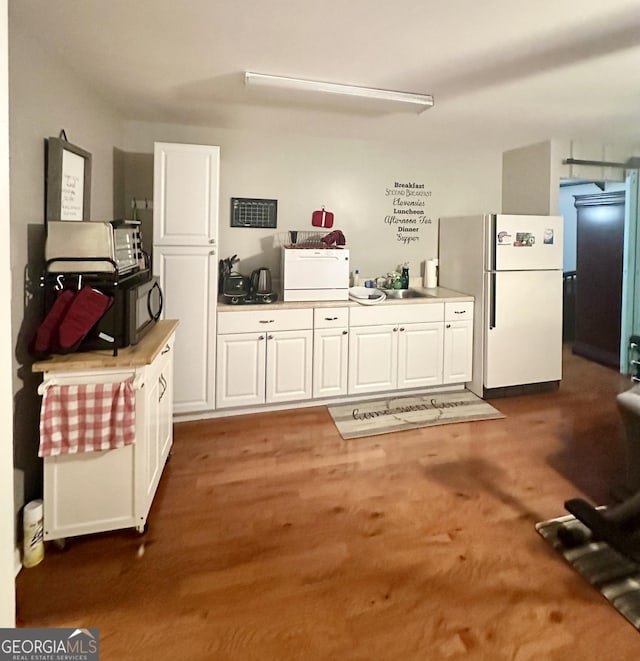 kitchen featuring freestanding refrigerator, white cabinets, and a sink
