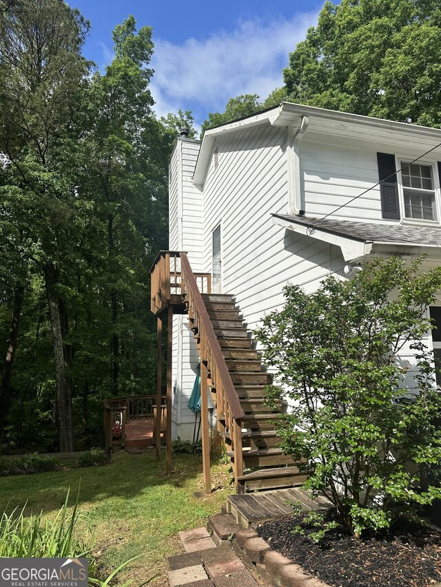 view of property exterior featuring stairs, a yard, a chimney, and a deck