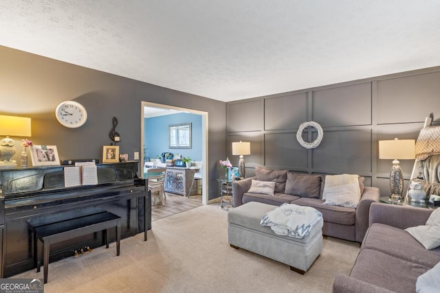 living area with light carpet, a decorative wall, and a textured ceiling