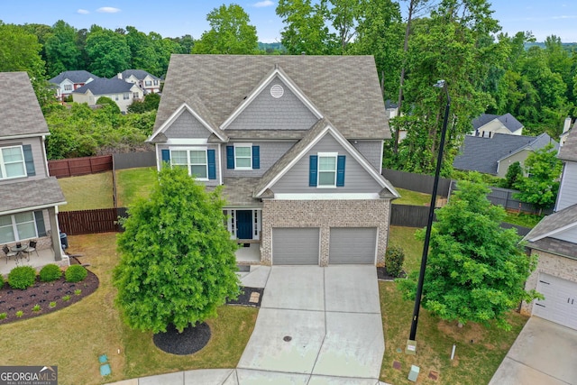 craftsman-style home featuring concrete driveway, fence, and a front lawn