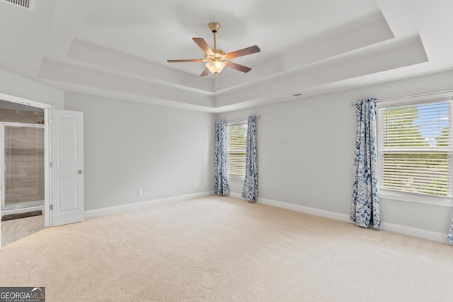 spare room featuring visible vents, baseboards, ceiling fan, a tray ceiling, and carpet flooring