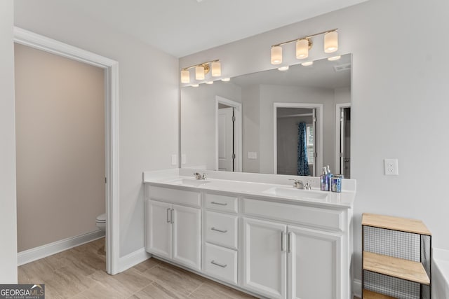 full bathroom with double vanity, a sink, baseboards, and toilet