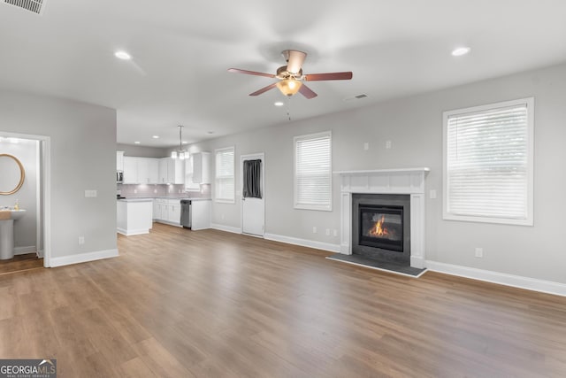 unfurnished living room with a ceiling fan, visible vents, wood finished floors, baseboards, and recessed lighting