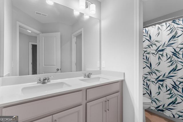 bathroom with visible vents, a sink, double vanity, and toilet