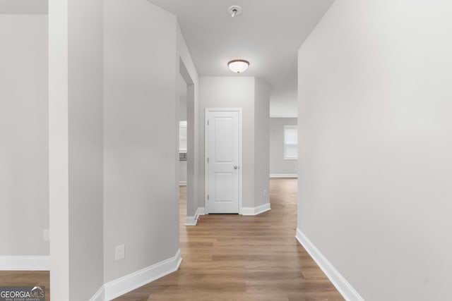 corridor with baseboards and wood finished floors