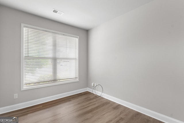 empty room with baseboards, visible vents, and wood finished floors