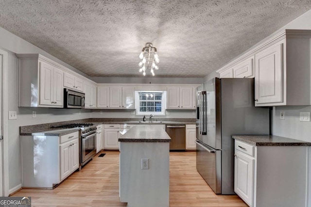 kitchen featuring a sink, light wood-style flooring, appliances with stainless steel finishes, and a kitchen island