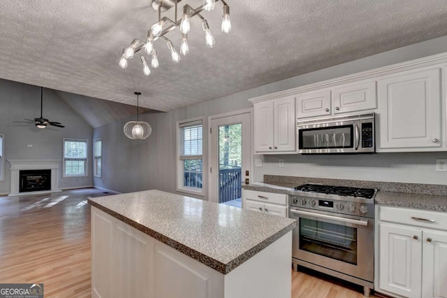 kitchen with appliances with stainless steel finishes, white cabinets, vaulted ceiling, and light wood-type flooring