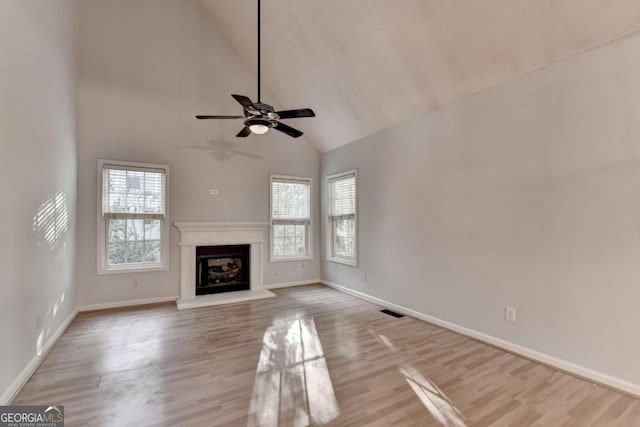 unfurnished living room featuring baseboards, a fireplace with raised hearth, a ceiling fan, and wood finished floors