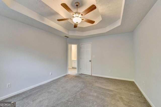 spare room with baseboards, carpet flooring, ceiling fan, and a tray ceiling