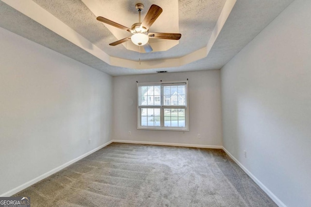 spare room with baseboards, carpet, and a tray ceiling