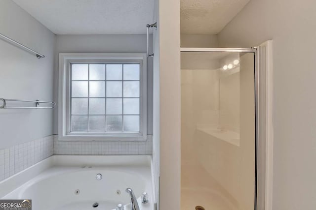 bathroom with a whirlpool tub, a shower stall, and a textured ceiling