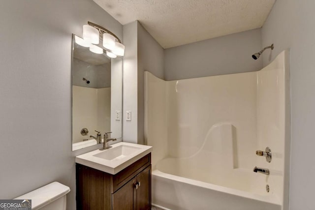 bathroom featuring vanity, a textured ceiling, washtub / shower combination, and toilet