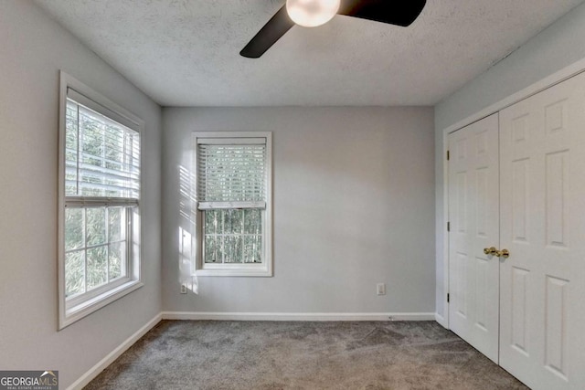 unfurnished bedroom featuring baseboards, multiple windows, and carpet flooring