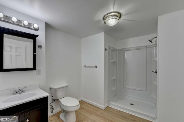 full bath featuring walk in shower, wood finished floors, vanity, baseboards, and toilet