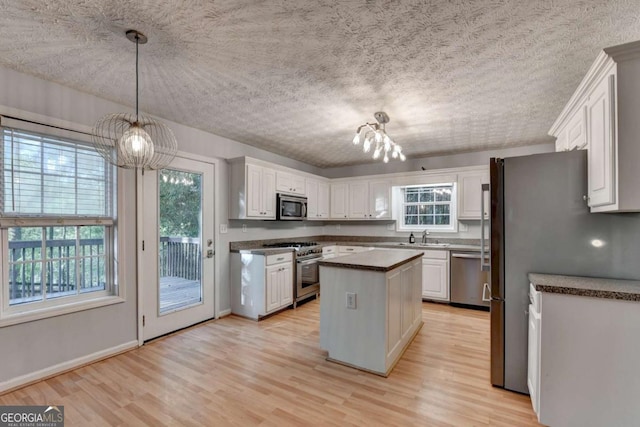 kitchen featuring dark countertops, a notable chandelier, light wood finished floors, stainless steel appliances, and a kitchen island