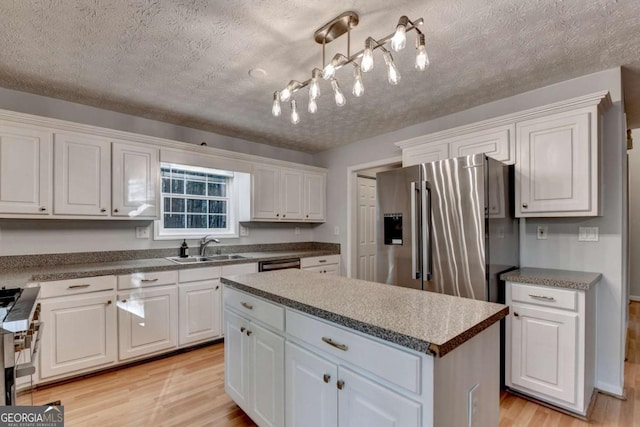 kitchen featuring white cabinets, stainless steel appliances, a sink, and light wood-style floors
