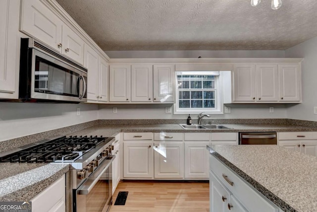 kitchen with light wood-style floors, a sink, white cabinets, and stainless steel appliances