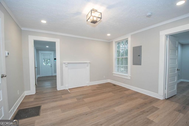 spare room featuring electric panel, a textured ceiling, visible vents, wood finished floors, and baseboards