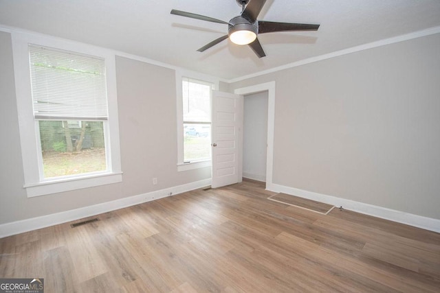 interior space featuring crown molding, baseboards, light wood-style flooring, and visible vents